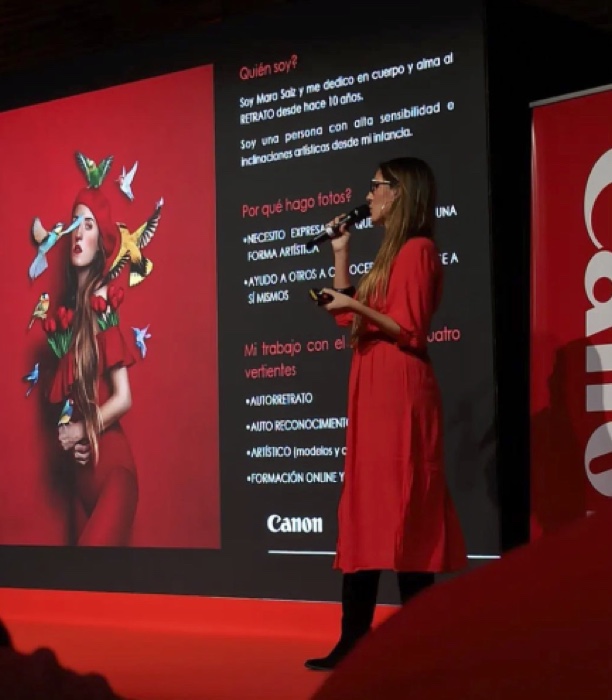 Mara Saiz impartiendo una ponencia sobre retrato en un escenario, con el logo de Canon detrás